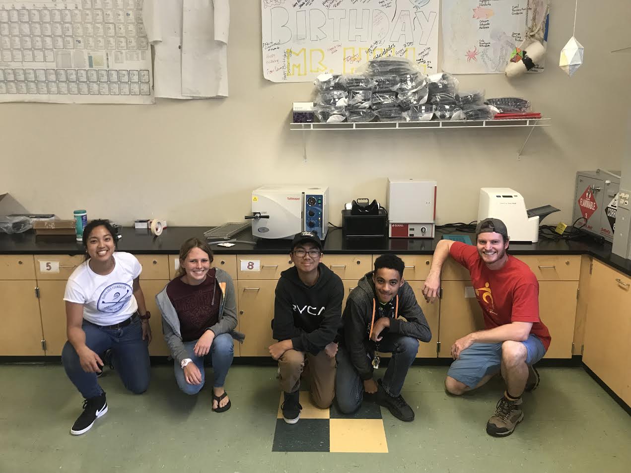 Group of students smiling in front of water testing equipment